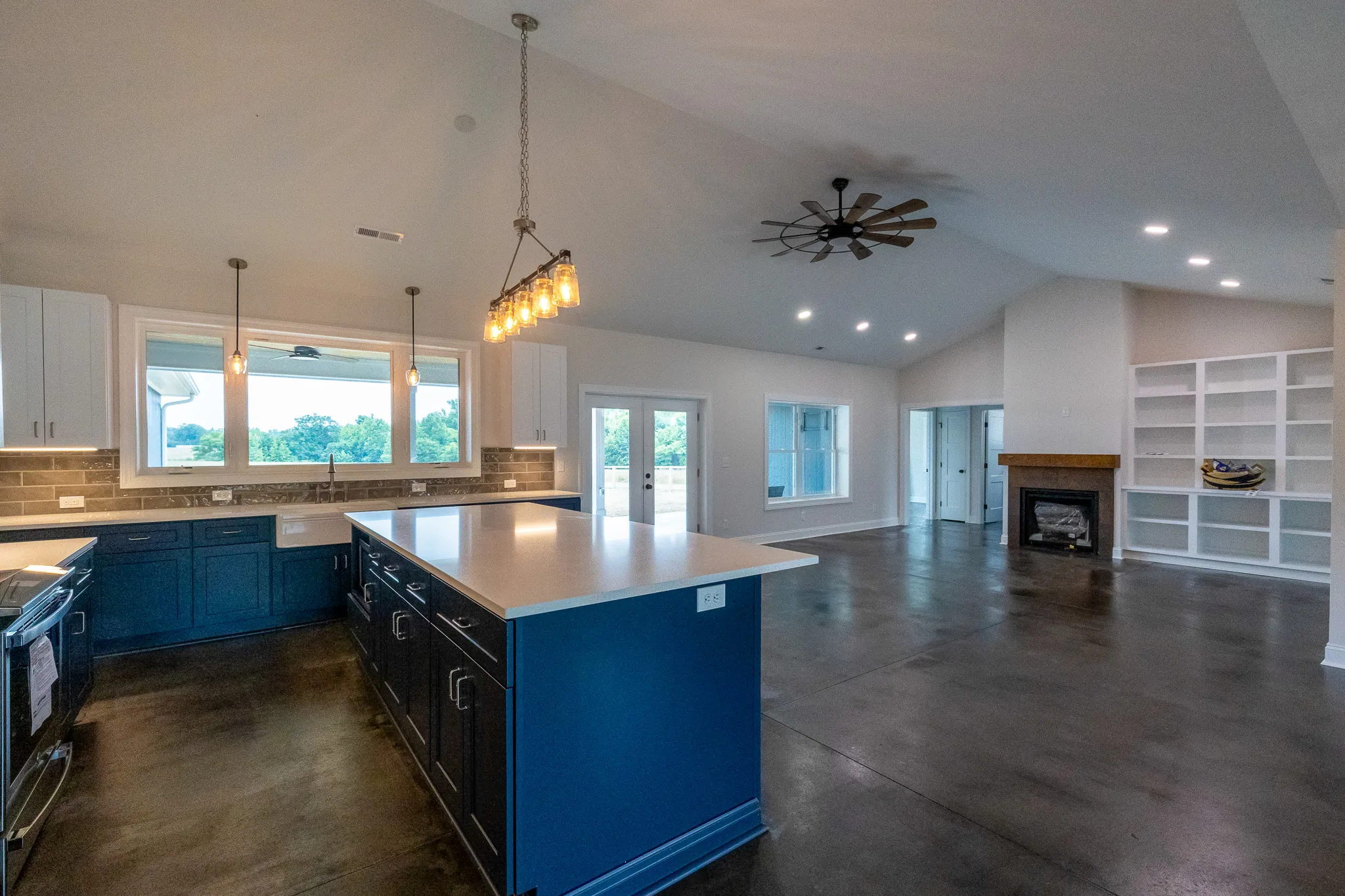 Blue-Juniper-002 | Hug Construction Open kitchen and living area with a blue island, fireplace, and white built-in shelving