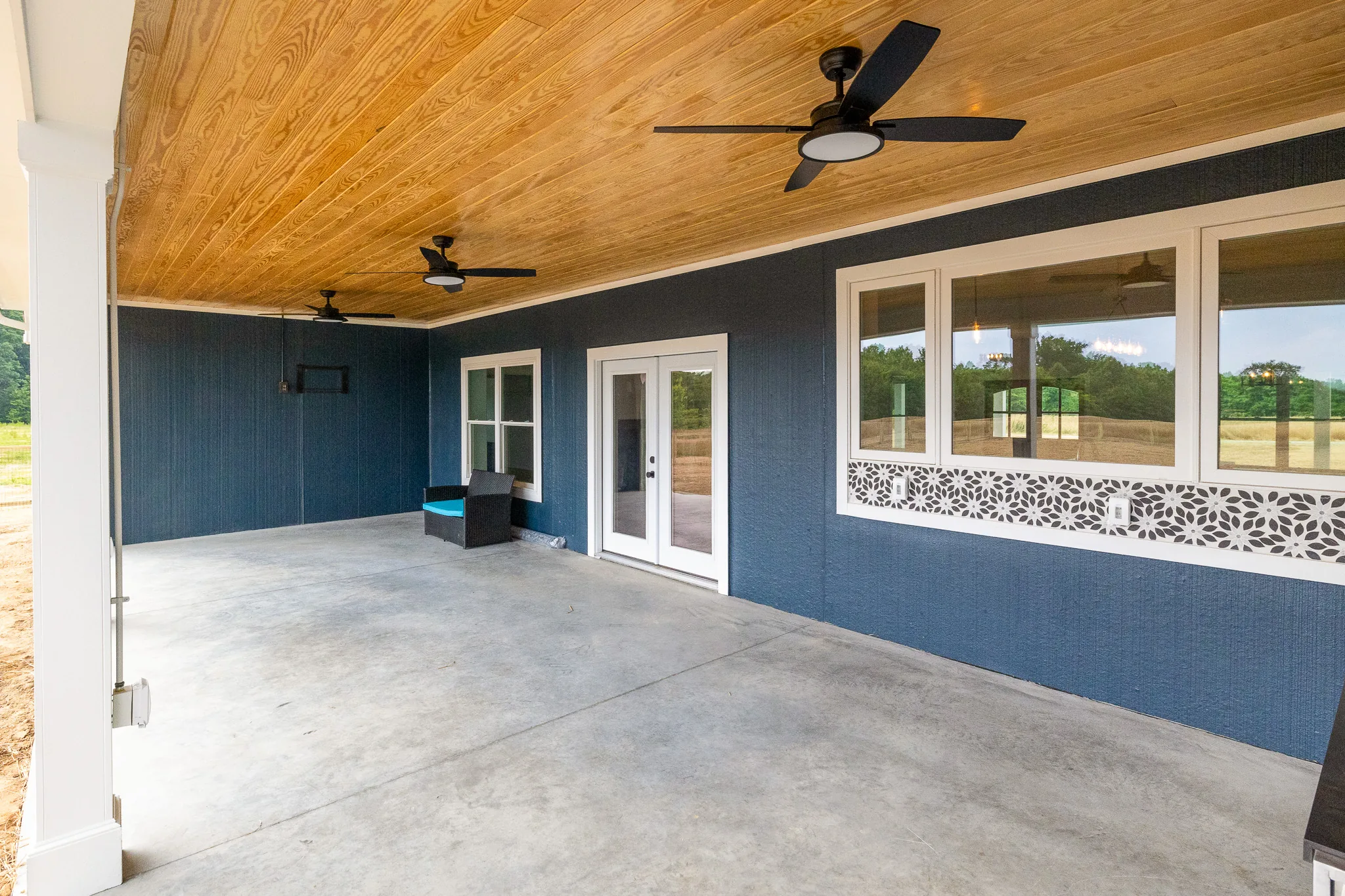 Blue-Juniper-003 | Hug Construction Covered back porch with a stained wood ceiling and black ceiling fans