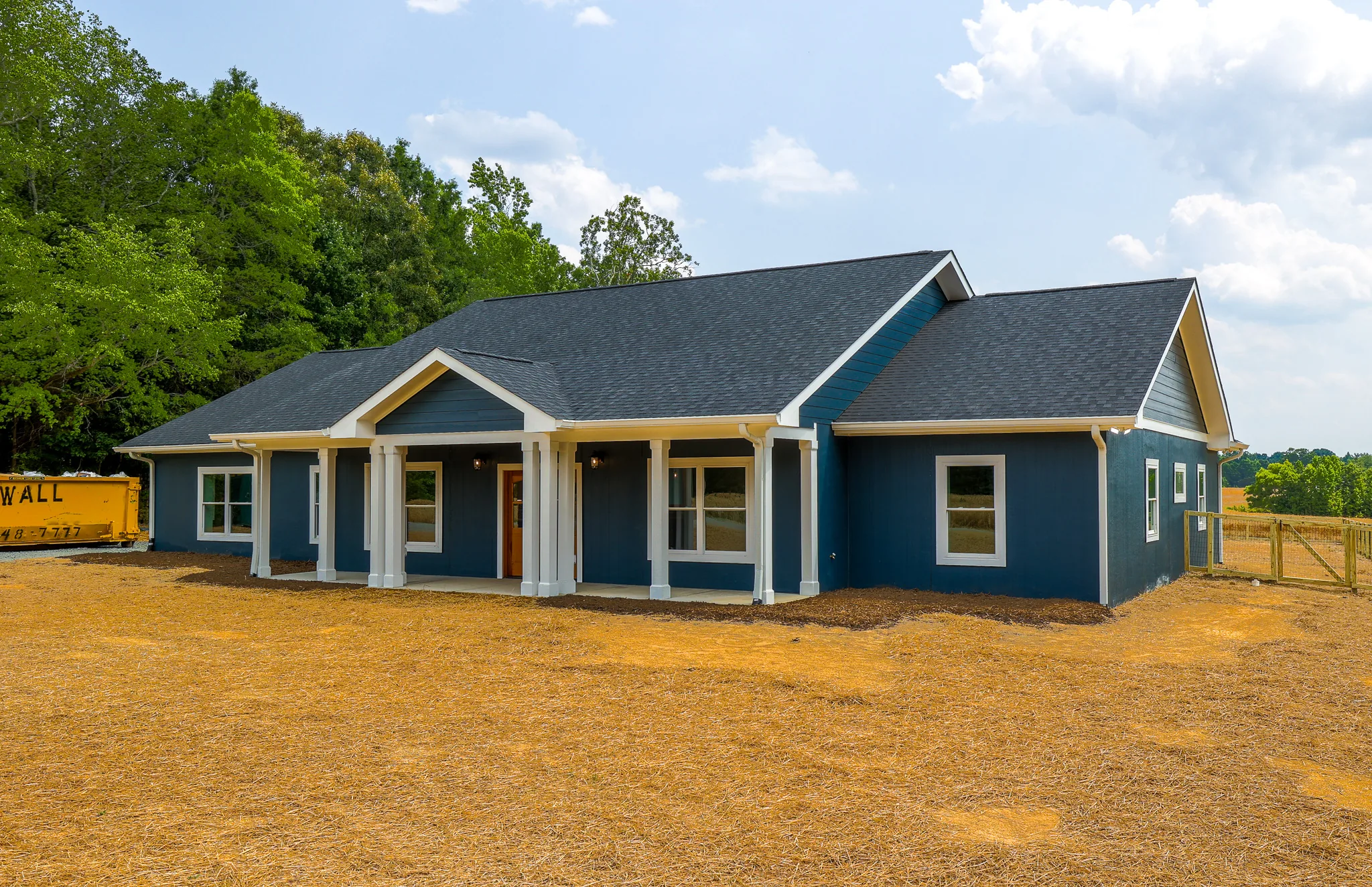 Angled view of the front porch and blue siding from the side yard