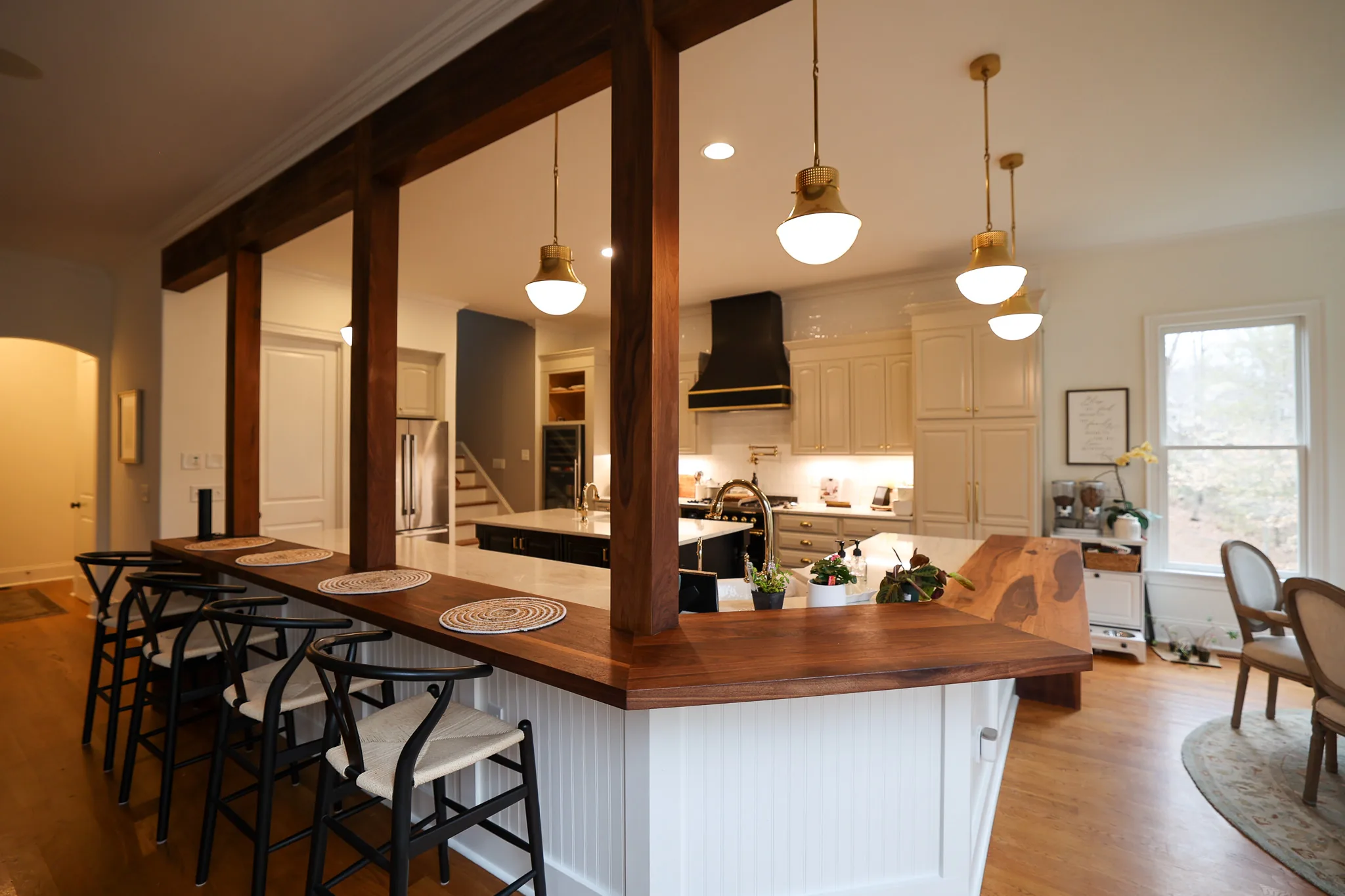 Wood breakfast bar with black wishbone stools framed by post and beam openings