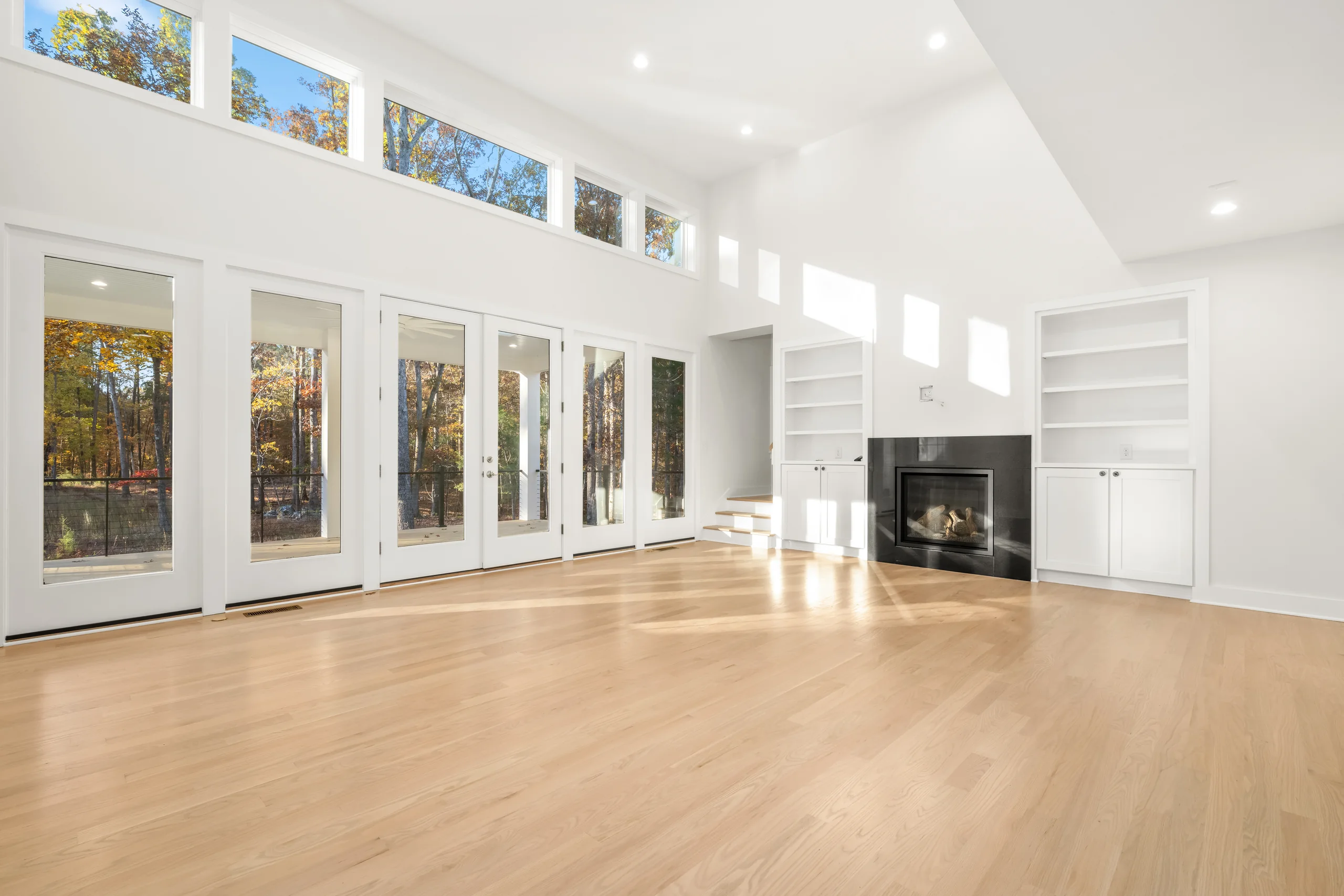 Loblolly-Pine-004 | Hug Construction Open living room with tall windows, clerestory windows, and a fireplace